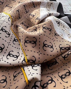 Close-up of twill silk scarf with monogram pattern and bright yellow border accent