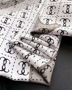 Close-up of geometric pattern silk scarf with elegant brown and grey border trim