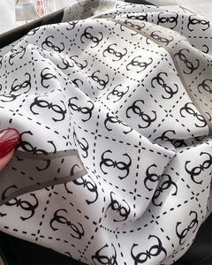 Detailed close-up of silk-like scarf featuring classic black and white monogram pattern
