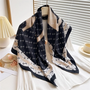 Elegant black and beige twill silk scarf with chain pattern on a white top with decor