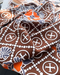 Macro detail of silk scarf featuring floral patterns and geometric logo prints