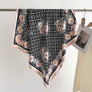 Detail of floral and geometric print scarf with contrast hem hanging on a wooden hanger