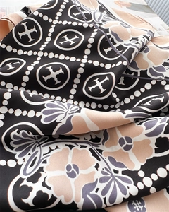 Detailed view of floral pattern and branding on a 90cm square silk scarf fabric texture