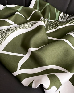 Gros plan sur un foulard en soie vert foncé avec imprimés floraux et texture sergé