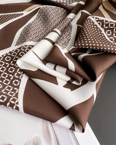 Gros plan d'un foulard en soie avec motifs géométriques café et texture de tissu sergé