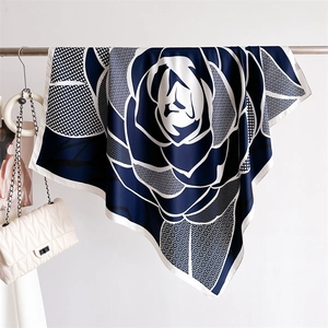 Détail d'un foulard en soie à fleurs bleu marine et blanc avec un sac à main blanc