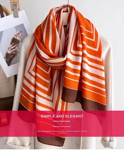 Close-up of elegant silk-feel scarf with geometric orange and brown stripes on a coat