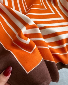 Detail view of silk-feel scarf showing diagonal twill texture and geometric patterns