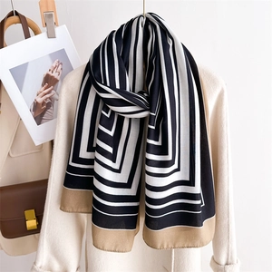 Detail of elegant black and white striped long scarf with khaki borders and silk texture