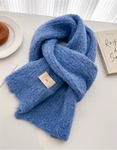 Detail showing royal blue knit scarf texture with a white woven label and fuzzy mohair finish