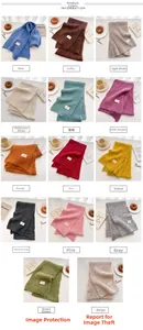 Flat lay of knit wool scarves in 14 colors with soft texture and minimalist brand tags