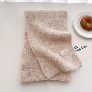 Detail of soft cream knit wool scarf with minimalist ins label on white desktop