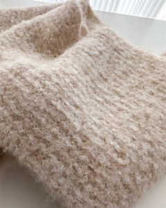 Detailed macro view of beige bouclé knit texture on thick winter wool scarf shawl