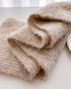 Close-up of beige wool knit scarf showing soft fluffy texture and premium fiber details