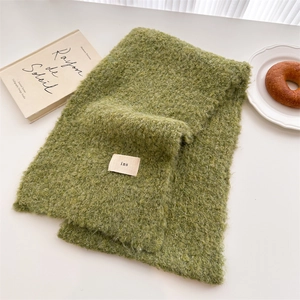 Close-up of grass green knit scarf with soft wool texture and minimalist ins tag