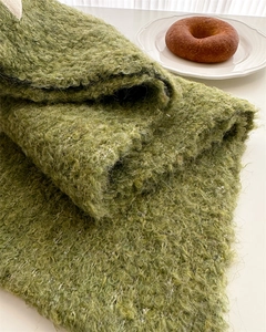 Close-up of olive green boucle knit wool scarf showing thick and soft boucle texture