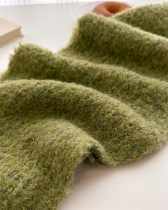 Detail of green bouclé knit texture and soft wool material of this winter scarf