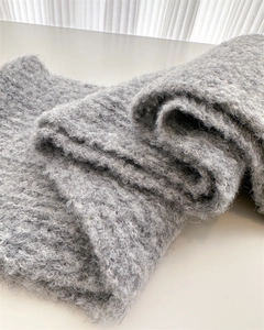 Close-up of thick grey knitted wool scarf showing soft texture and warm chunky yarn material