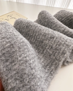 Close-up of soft grey curly wool texture on a stylish minimalist knitted winter scarf