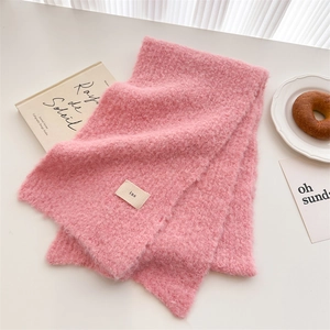 Flat lay of pink mohair knit scarf with ins label on white desk with French book