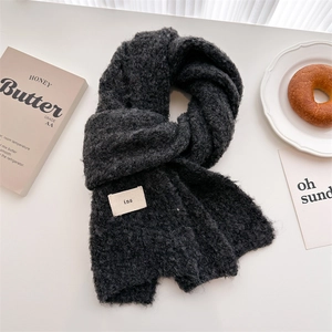 Detail of dark grey knit scarf texture with ins label on a minimalist table setting