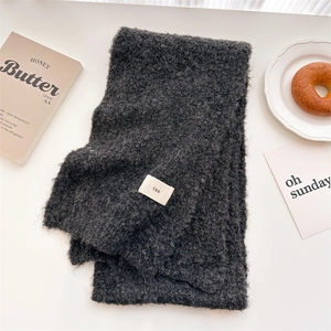 Close-up of a dark grey teddy fleece scarf texture featuring a white ins woven label