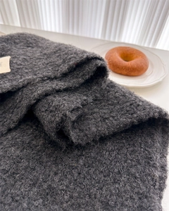 Macro shot of dark grey boucle wool scarf with decorative label and thick texture