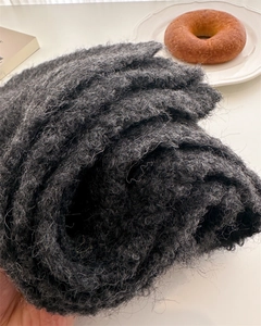 Macro shot of dark charcoal grey bouclé knit wool scarf with thick curly fiber texture