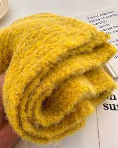 Detailed macro shot showing vibrant yellow knit scarf with textured curly wool yarn