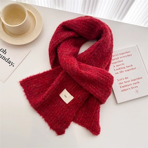Close-up of red knit scarf texture with ins label and fringe on a white tabletop