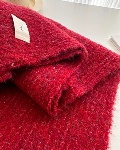 Macro shot of dark red knit scarf with textured loop pattern and minimalist label