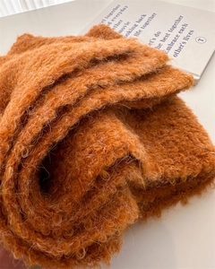 Detailed view of caramel bouclé knit scarf texture showing fluffy wool fibers and thick yarn