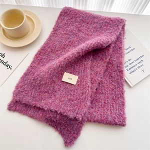 Detail of burgundy knitted scarf with ins label on a minimalist lifestyle background