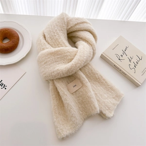 Detailed close-up of fluffy cream knit scarf with minimalist ins woven label detail