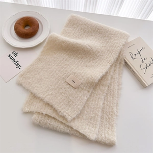 Detail of off-white wool knit scarf with ins label tag and soft fluffy texture