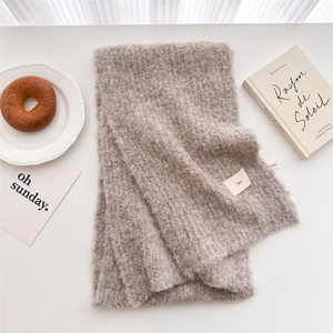 Detail shot of oatmeal wool knit scarf with ins label on a minimalist setup