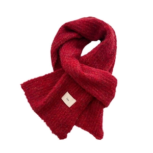 Minimalist red knit scarf with white ins label and soft wool texture for winter warmth