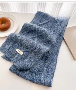 Detailed cable knit texture of a navy blue wool scarf with speckled pattern and tassel fringe