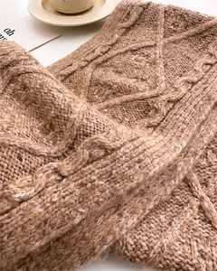 Close-up of brown chunky knit wool scarf featuring detailed diamond and cable patterns