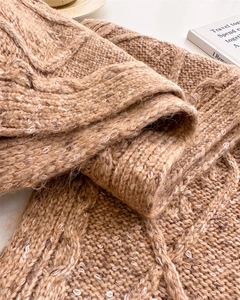 Close-up of beige cable knit wool scarf texture with soft fibers and premium winter warmth