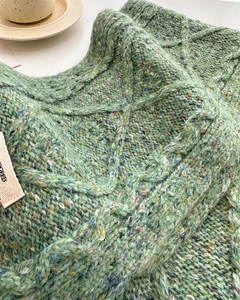 Close-up of green cable knit wool scarf texture showing thick marl yarn and diamond patterns