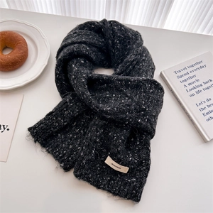 Close-up of thick knit wool scarf texture with brand label and frayed edge details