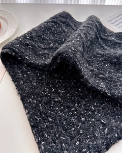 Close-up of thick grey mohair knit scarf texture with subtle shimmering white silk details
