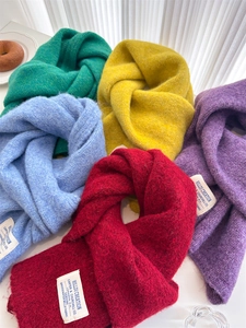Flat lay of colorful thick knit wool scarves with premium brand woven labels