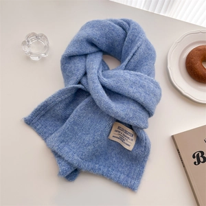 Sky blue knit scarf with vintage label on white background with winter lifestyle props