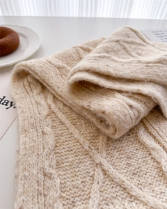 Close-up of oatmeal cable knit wool scarf with warm winter atmosphere setting