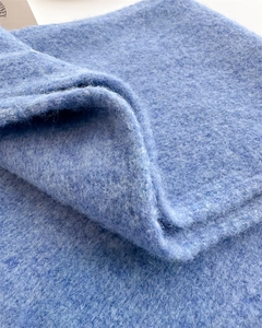 Close-up of light blue mohair knit fabric showing soft fluffy texture and wool grain