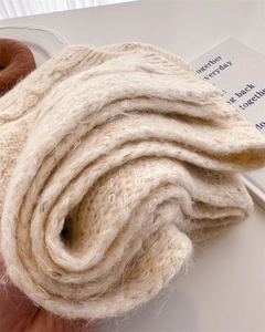 Macro shot of thick cream white chunky knit scarf with cozy wool texture and tweed finish