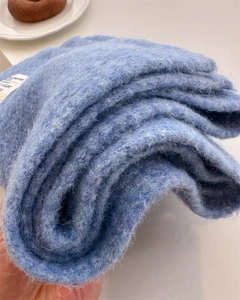 Close-up of light blue knit scarf with soft wool texture and white woven brand label