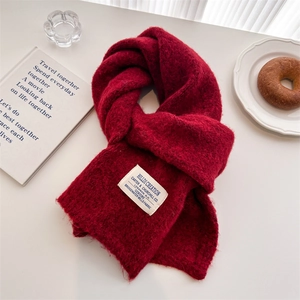 Detail of red wool knit scarf with vintage fabric label on a cozy winter breakfast table
